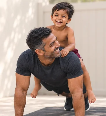 Father doing a push-up on a mat with his son on his back